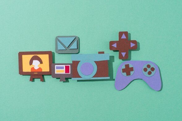 Manette de jeu, écran, appareil photo et téléviseur découpés dans du papier coloré