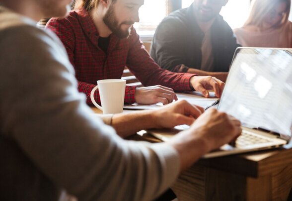 Groupe de personnes travaillant ensemble autour d'une table avec un ordinateur portable