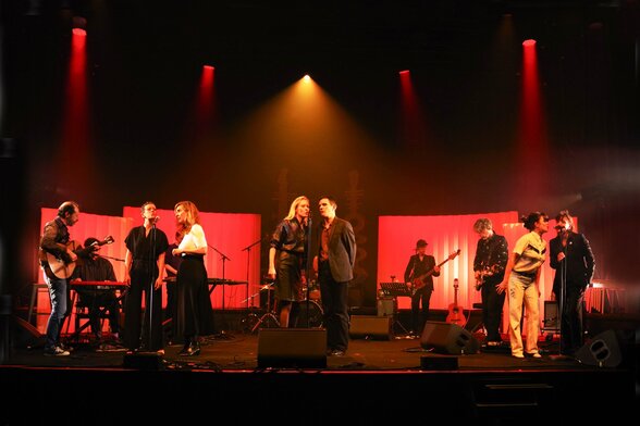 Musiciens et chanteurs sur une scène éclairée de rouge