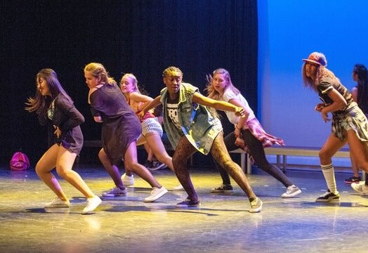 Groupe de danseurs en pleine performance hip-hop sur une scène éclairée