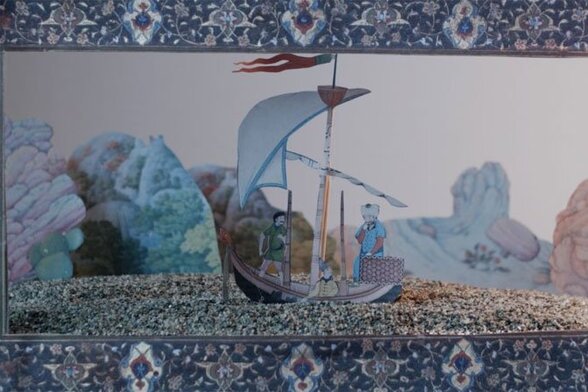 Image du film Zou : un petit bateau à voile entre des rochers, dans un cadre de tapis