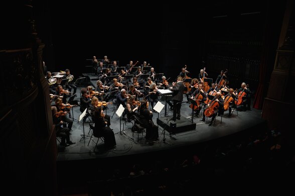 Orchestre de chambre en concert sur une scène sombre